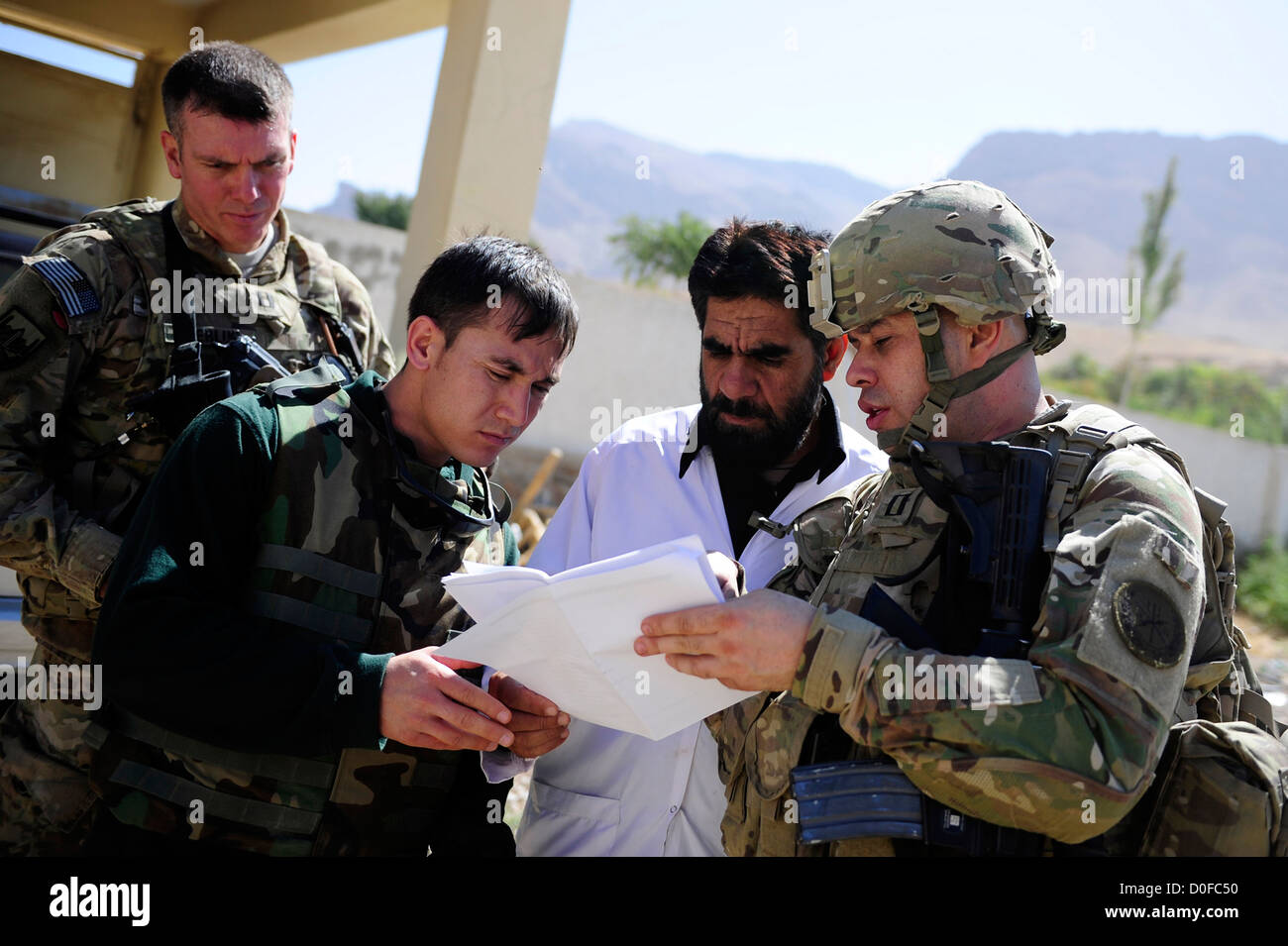 A US Navy engineer and a Navy physician's assistant go over design plans with a local doctor September 26, 2012 during a mission to Pur Chaman district, Farah province, Afghanistan. The mission marks the first time coalition forces have been to the Pur Chaman district in over a year. Stock Photo