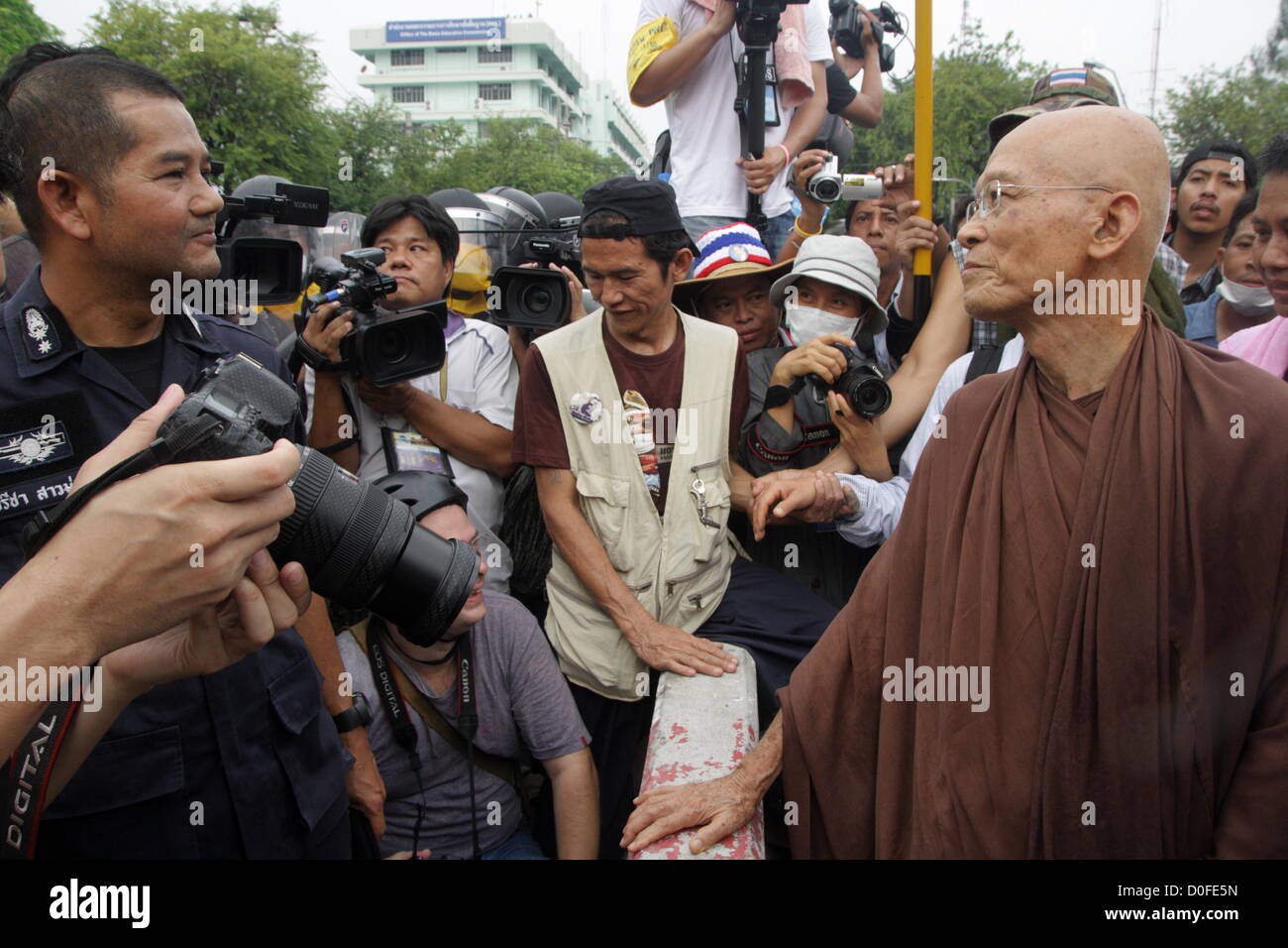 24 Nov 2012 , Bangkok , Thailand . Thai Buddhist monk speak with riot policemen . Thai police fired tear gas and detained dozens of people as tensions flared at an anti-Pitak Siam government protest .  The Siam Pitak group, which sponsored the protest, cited alleged government corruption and anti-monarchist elements within the ruling party as grounds for the protest. Police used tear gas and baton charges againt protesters. Stock Photo