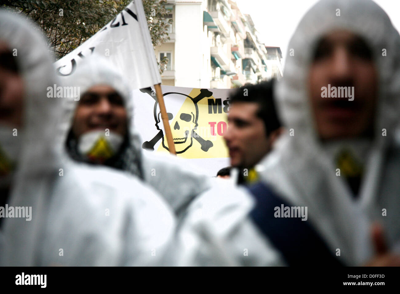 Thessaloniki,Greece. November 24, 2012. Young demonstrators wearing chemical protection suits and shout slogans. Thousands of people flooded the streets of Thessaloniki to protest against efforts by Hellas Gold, a subsidiary of the Canadian firm Eldorado Gold, to mine the Skouries quarry on Mount Kakkavos, in the Halkidiki peninsula and the city of Kilkis in northern Greece. Stock Photo