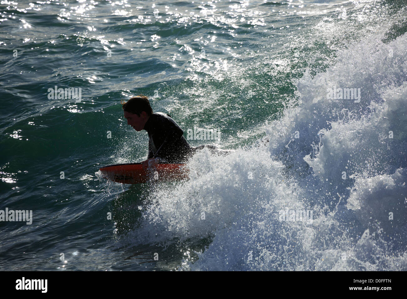 Surfer at Porthleven, Cornwall. A surfer shows intense concentration as he rides a wave lying on his bodyboard. Stock Photo
