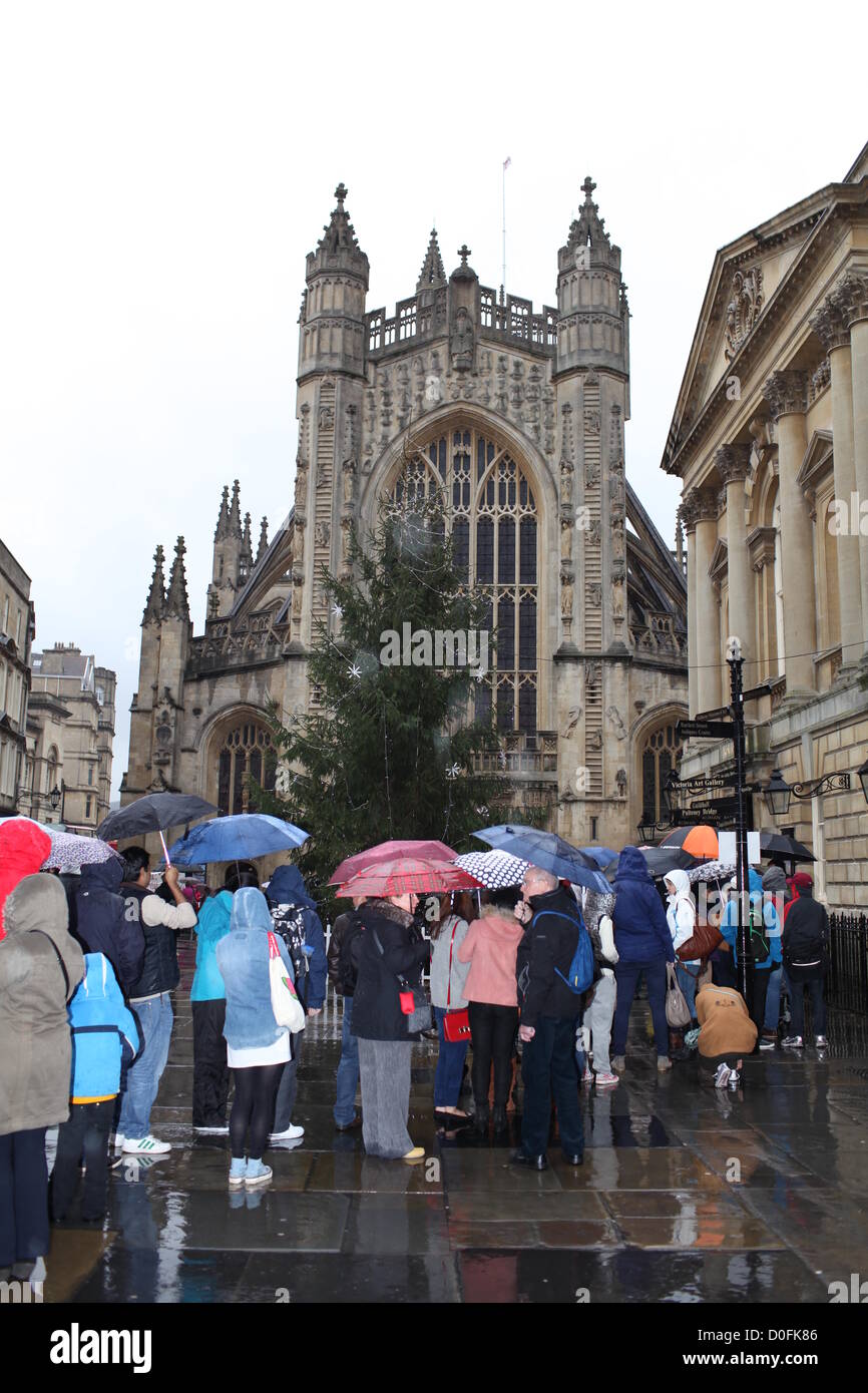 Bath, UK. 24th Nov, 2012. Tourists queue in the rain for the Roman Baths, in front of Bath Abbey and town Christmas tree Stock Photo