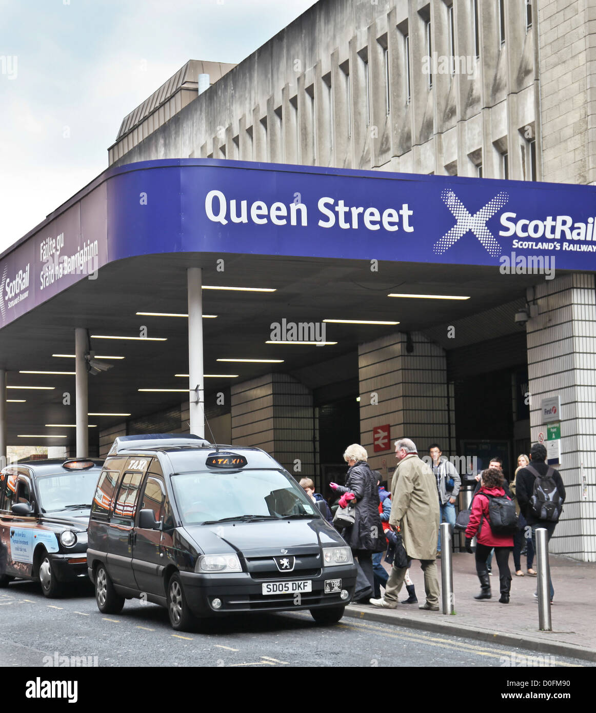 Passengers going into Queen Street Station, Glasgow, and arriving family going into a taxi, Dundas Street. Entrance canopy sign Stock Photo
