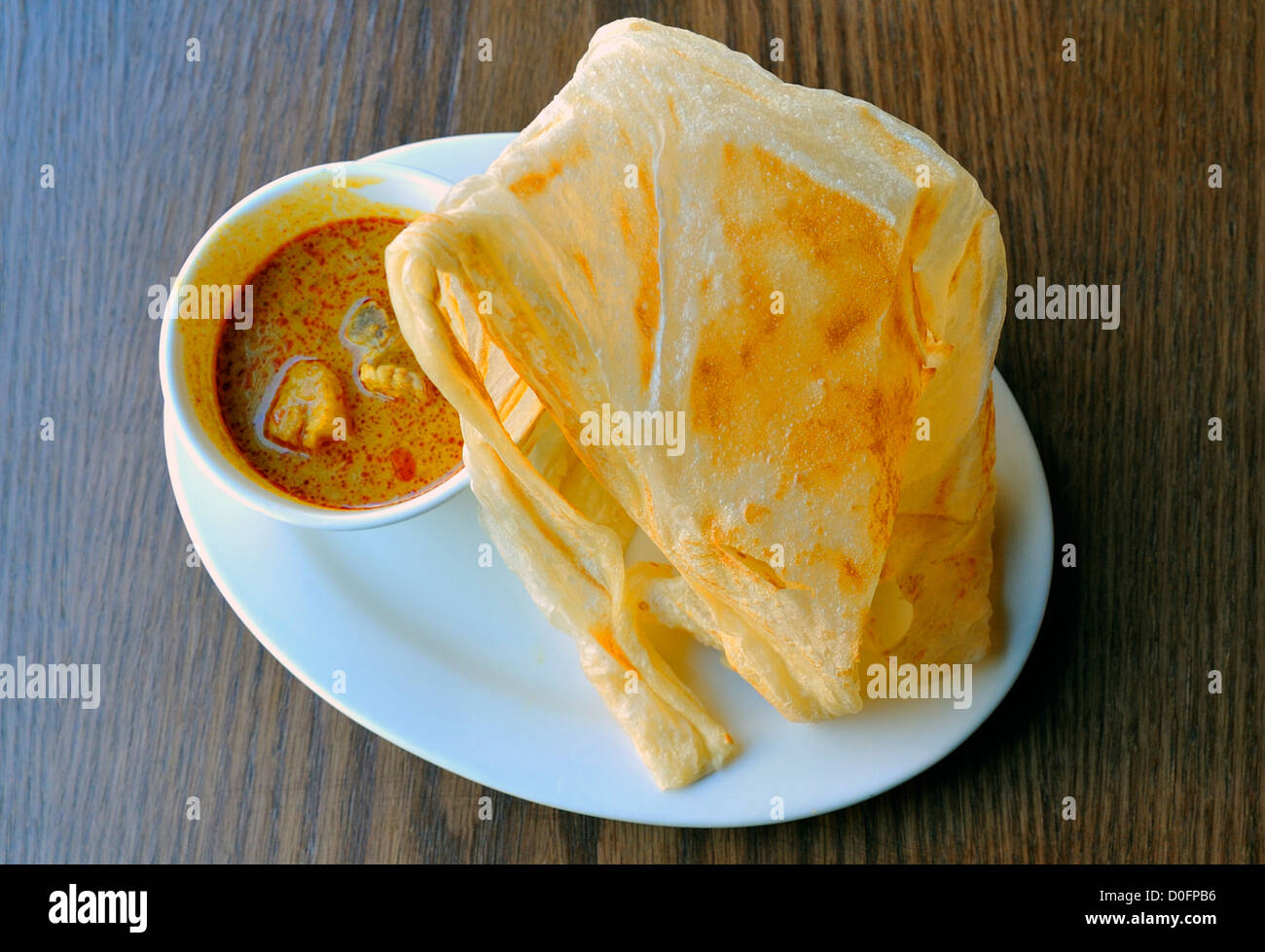 Roti canai, a Malaysian - Indonesian appetizer of a thin Indian pancake and spicy dip Stock Photo