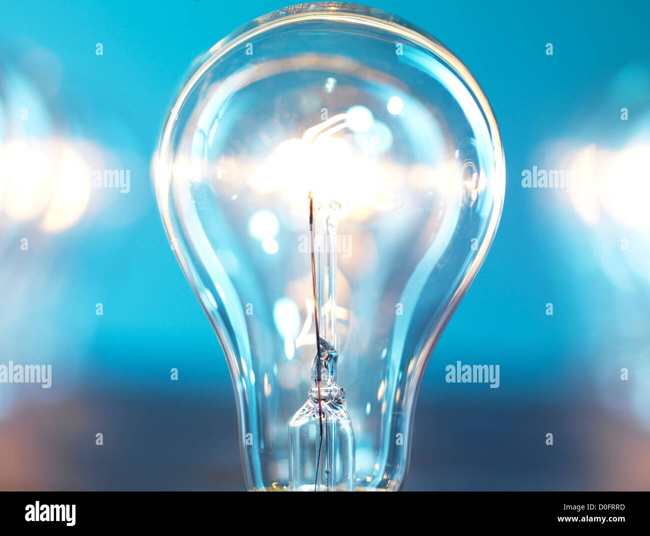 Closeup of lit up incandescent light bulb on blue background. Power