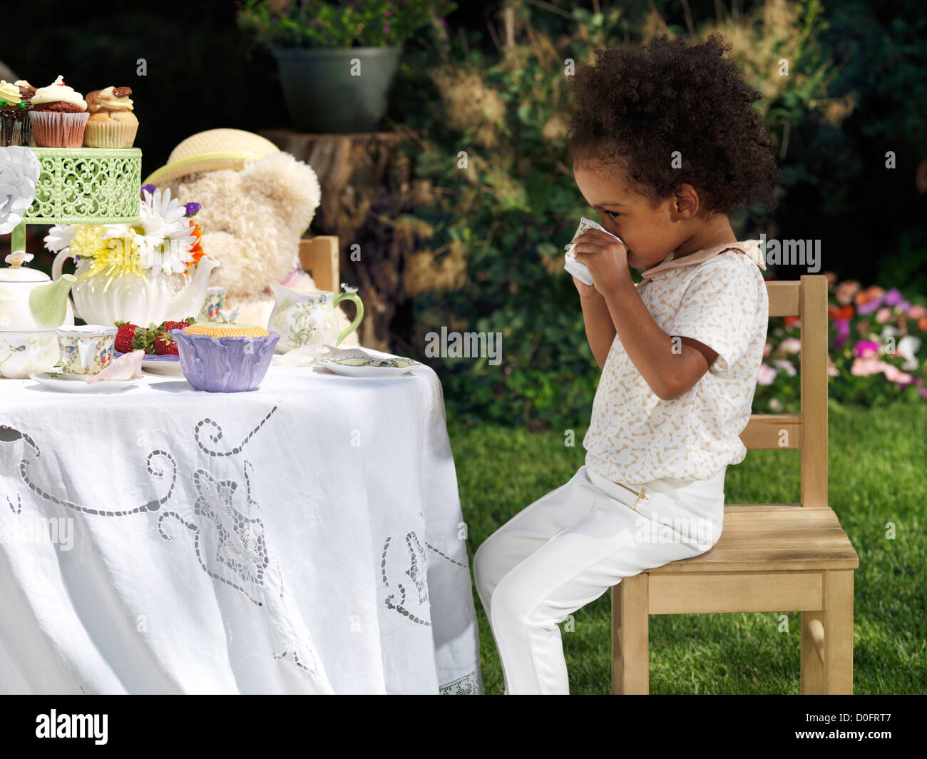 License available at MaximImages.com - Happy smiling girl having an outdoor summer party. Drinking tea with cupcakes. Stock Photo