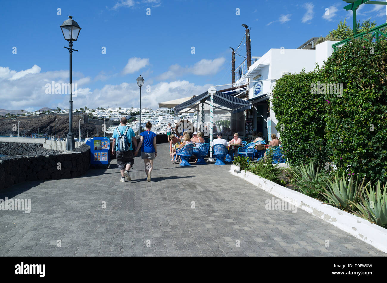 dh  PUERTO DEL CARMEN LANZAROTE Tourist couple walking by outdoor cafe people sitting relaxing holiday Stock Photo