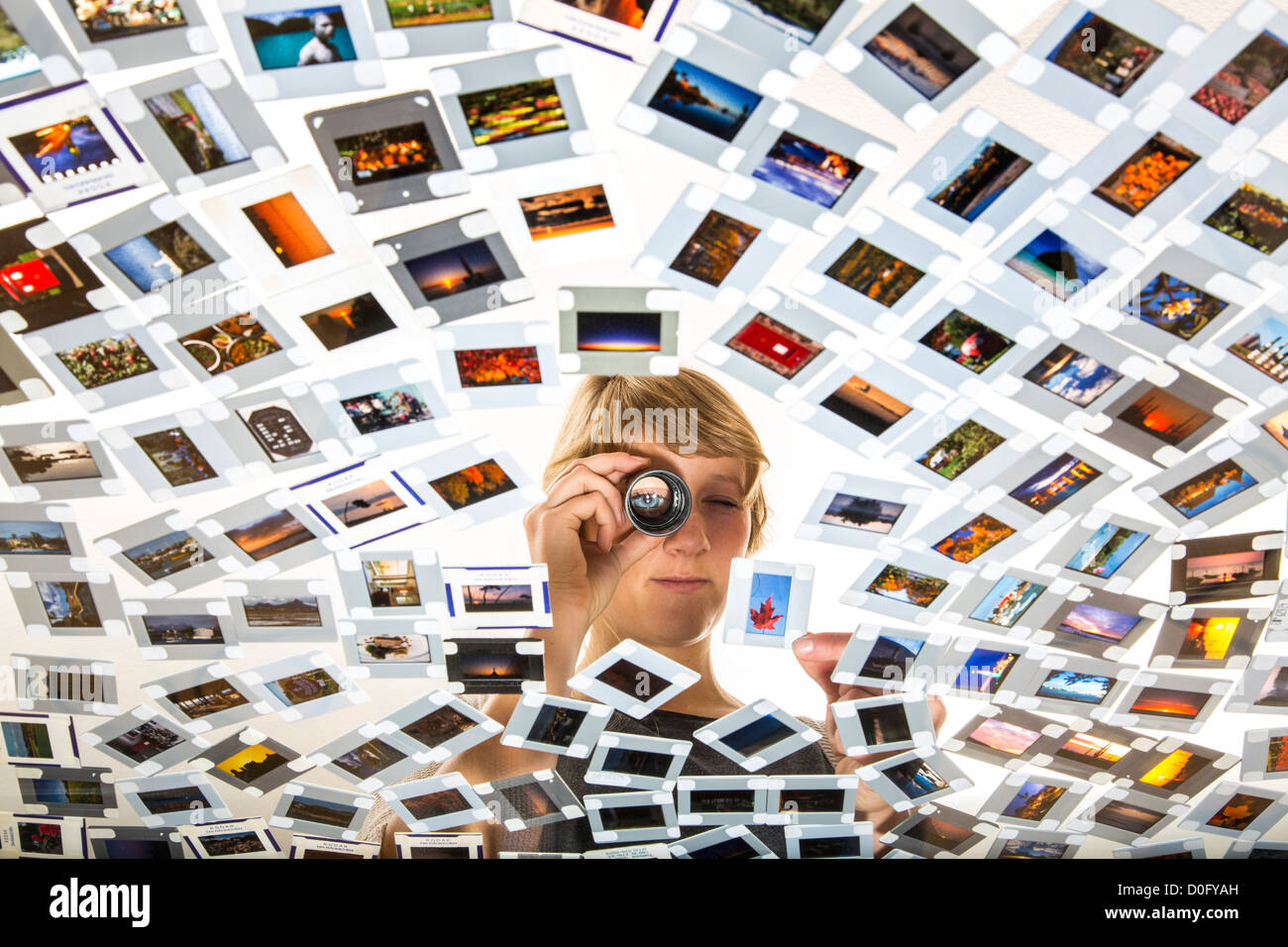Woman, photo editor,  is looking at slides, photos, at a light table. Picture editing. Analog photography. Stock Photo