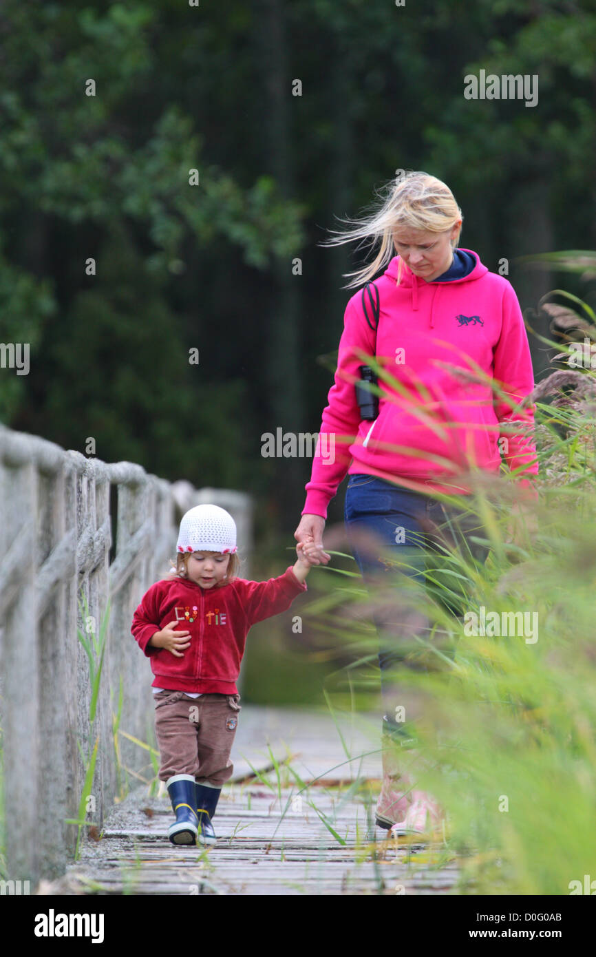 Child walking with her mother in nature. Mother has binoculars. Stock Photo
