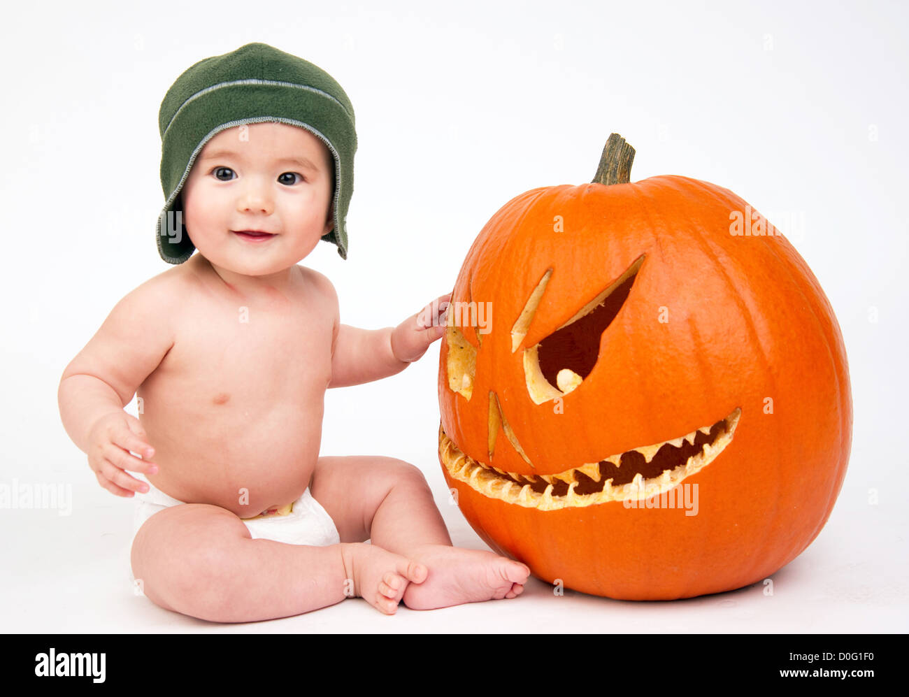 Young male sits next to a pumpkin on white Stock Photo