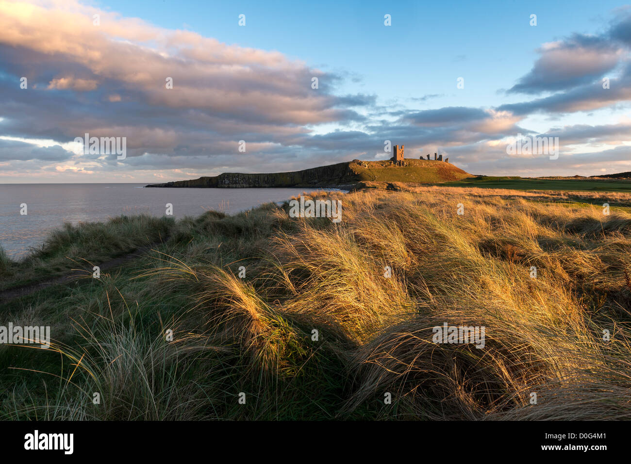 Dunstanburgh Castle, just prior to sundown bathed in the last of the afternoon light Stock Photo