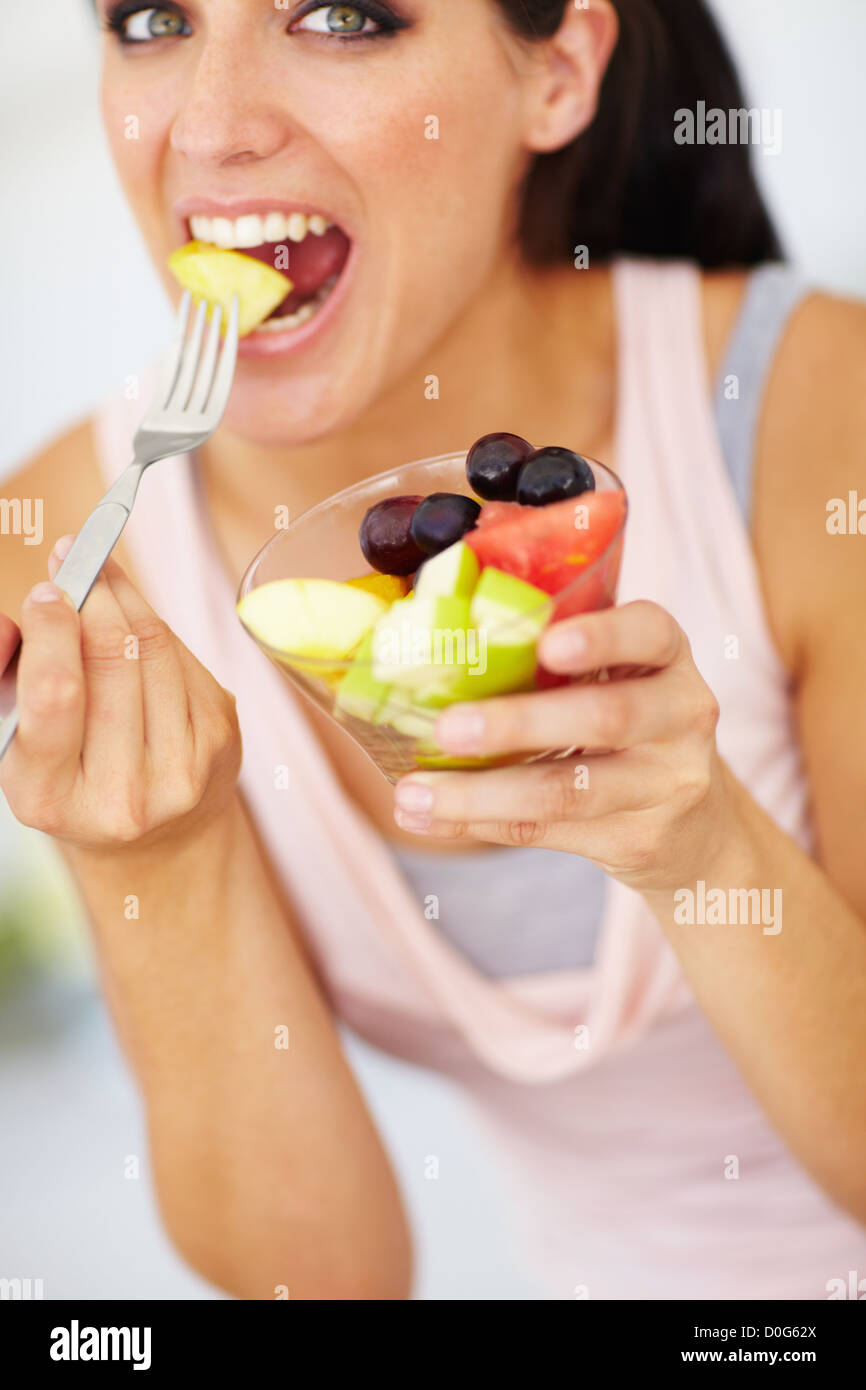 An attractive young woman eating a piece of apple from her fruit salad Stock Photo