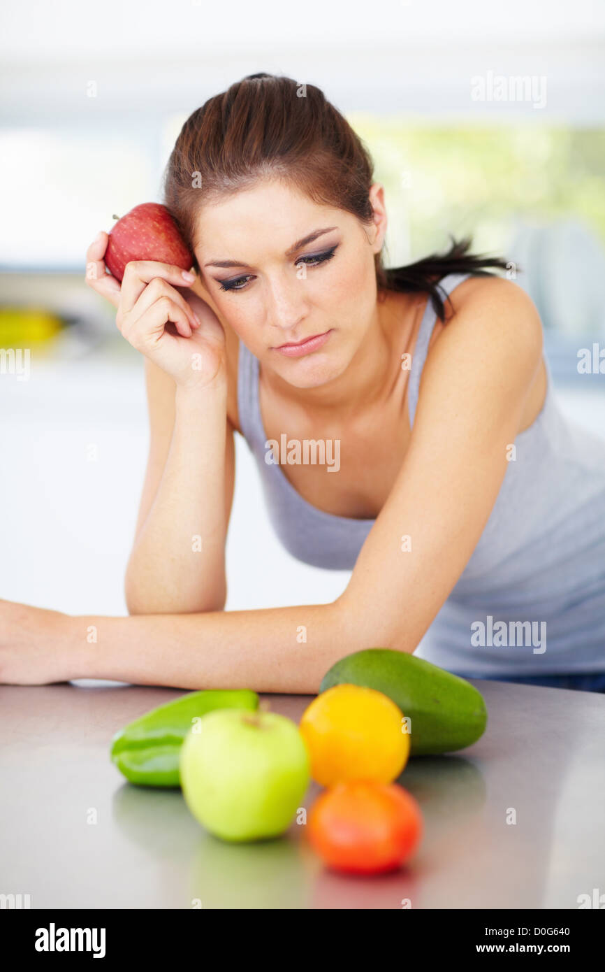 An attractive young woman deciding staring at the fruit and vegatables in front of her Stock Photo