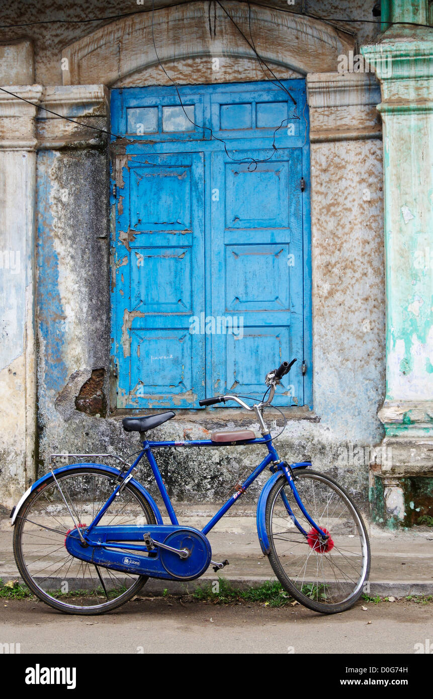 A blue bicycle in front of a blue door in Cochin, Kerala India Stock Photo