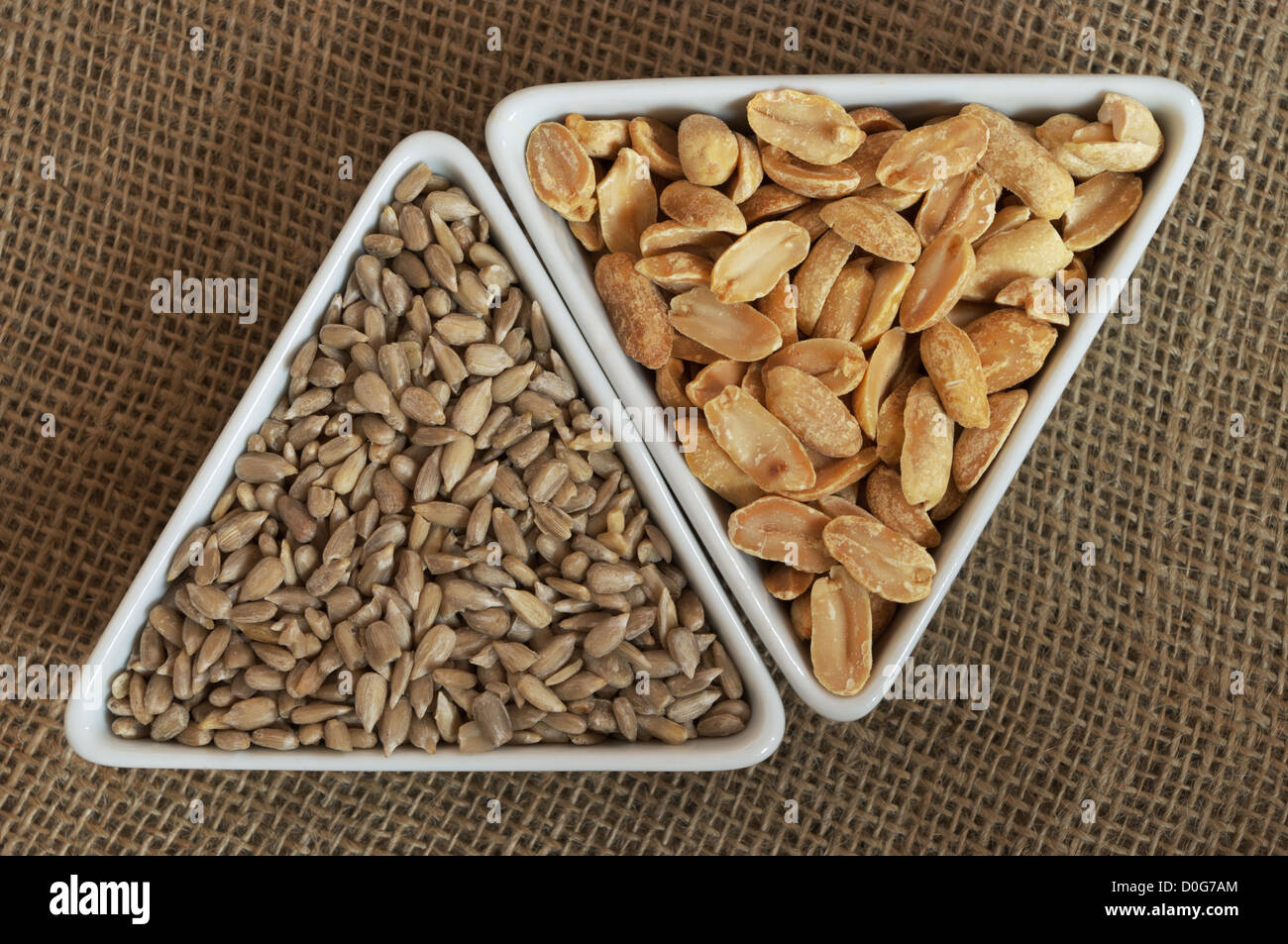 Peanuts and sunflower seeds in two triangular bowls top view still life. Stock Photo