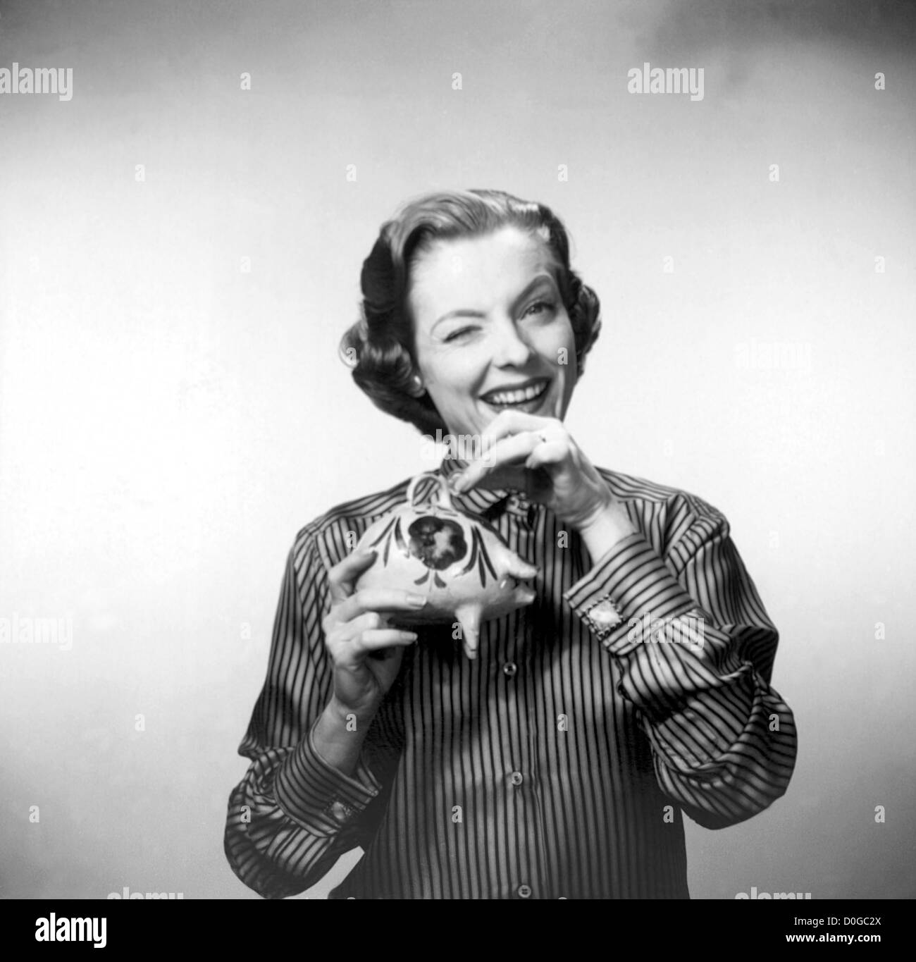 Woman putting coin in a piggy bank Stock Photo - Alamy