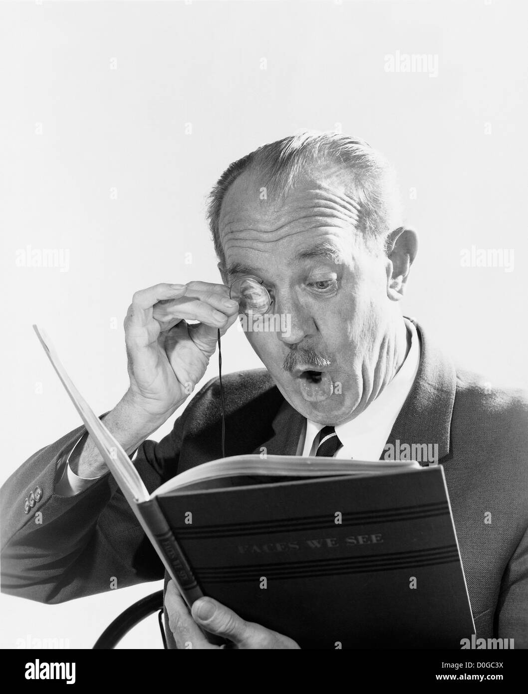 Black and white print of man with monocle looking at a book Stock Photo