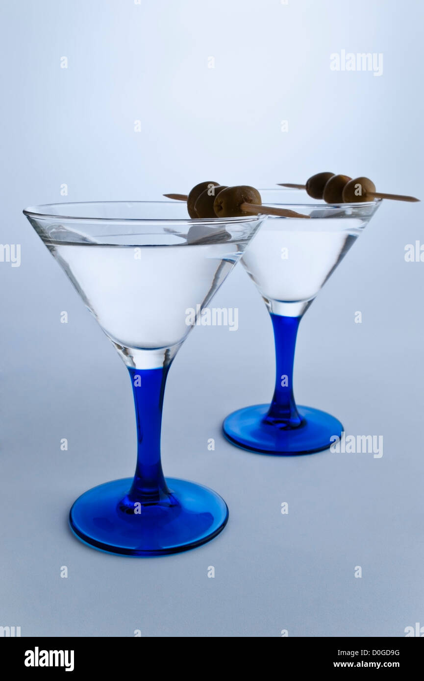 Two stylish Martini glasses on gray white background. Two Martini's with olives Stock Photo