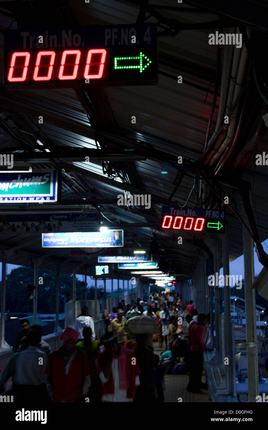 Early morning rush at an Indian Railway station. Digital screen for platform 4 shows the train number as zero. Stock Photo