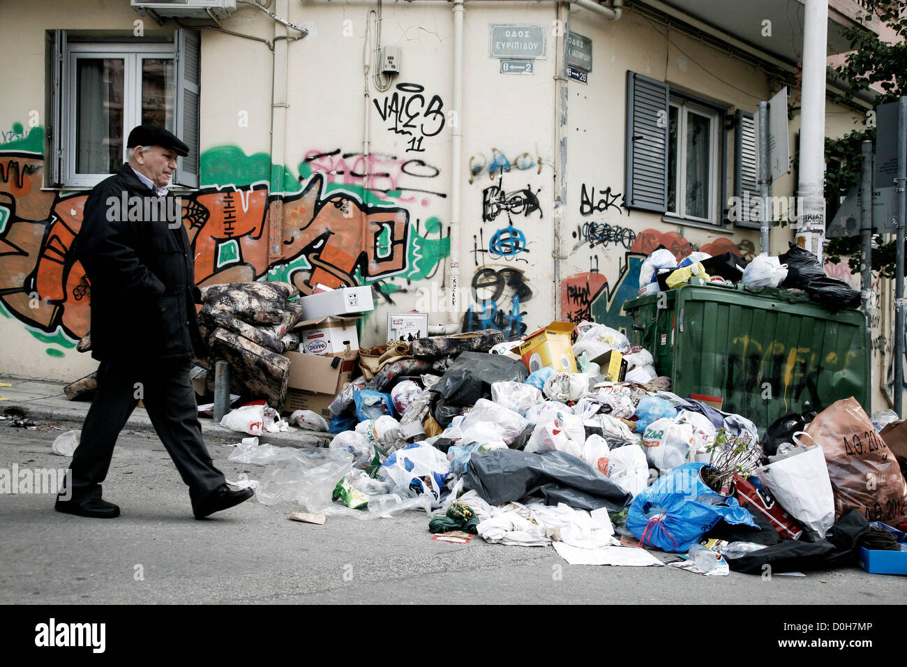 Thessaloniki, Greece. 26th November 2012. An elderly man walks past a pile of garbage. Today garbage collection in Thessaloniki begins again after ten days of striking by sanitation workers. The municipality said that it would take two to three days to clear up more than 2000 tonnes of garbage that had piled up during the protest. Stock Photo