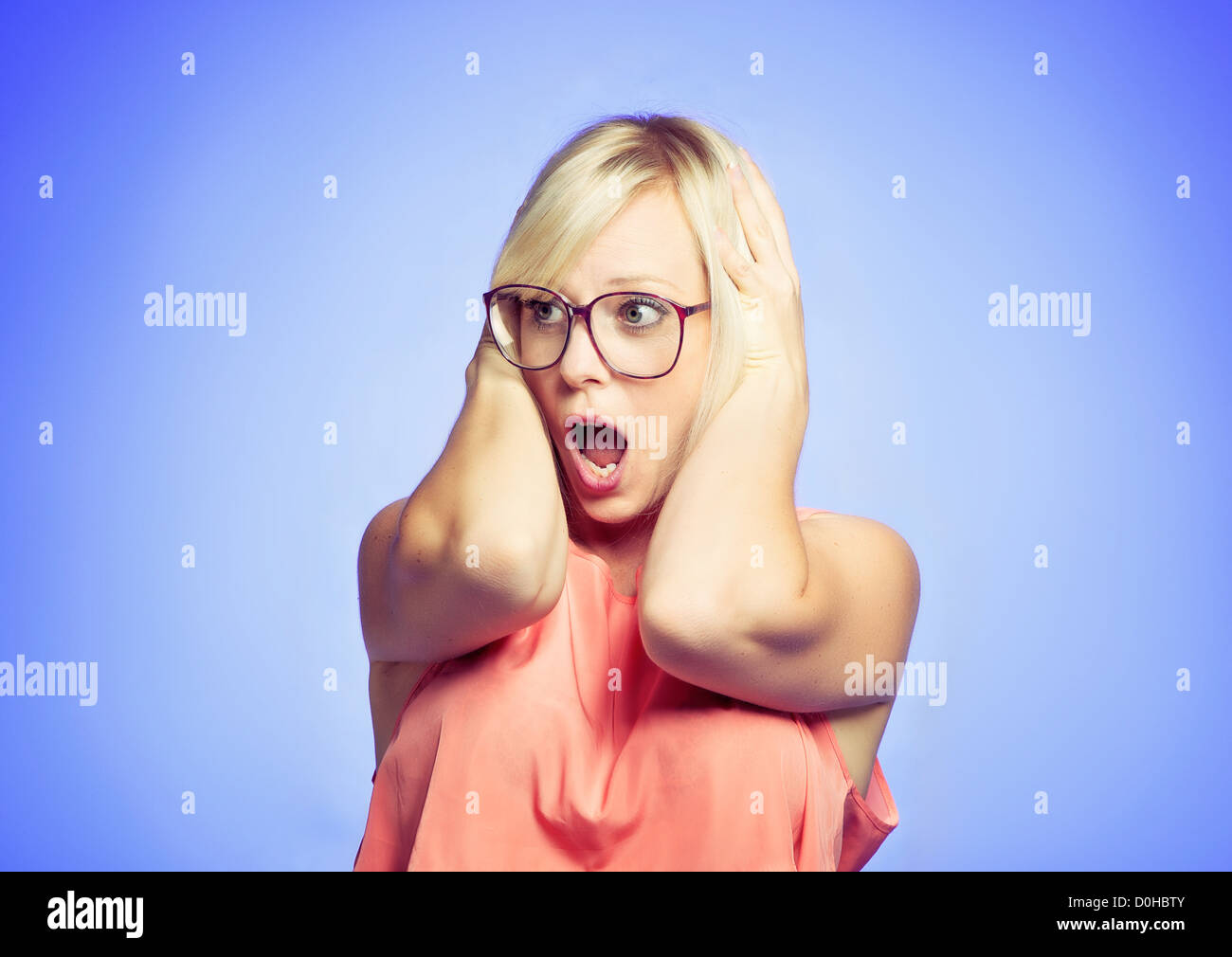 Panicking woman with her mouth open, isolated on blue background Stock Photo