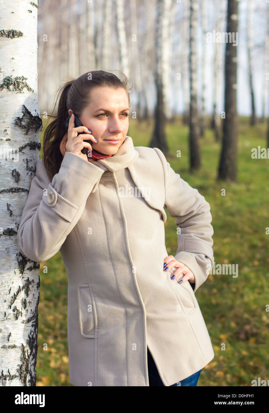 Autumn portrait of a girl under the birch telephoned Stock Photo