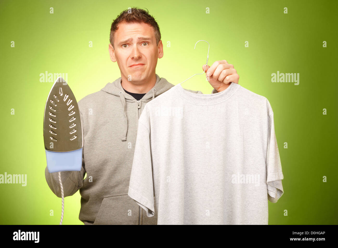 Man unhappy, confused and unsure being not prepared to ironing his clothes Stock Photo