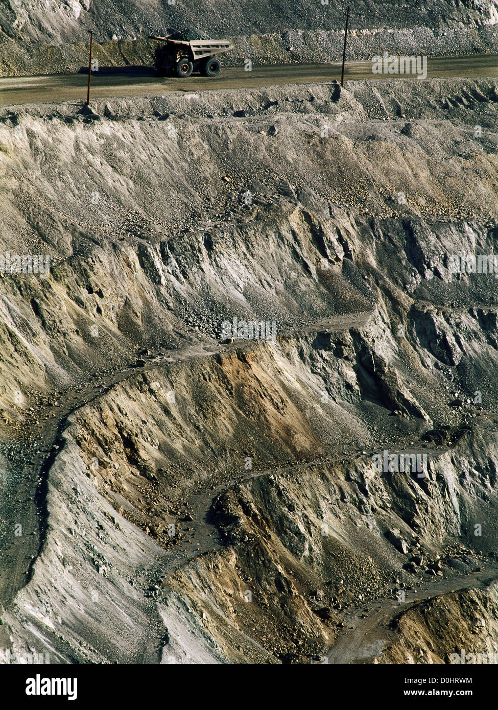 An Enormous Mining Truck Is Dwarfed by an Open Pit Mine Stock Photo