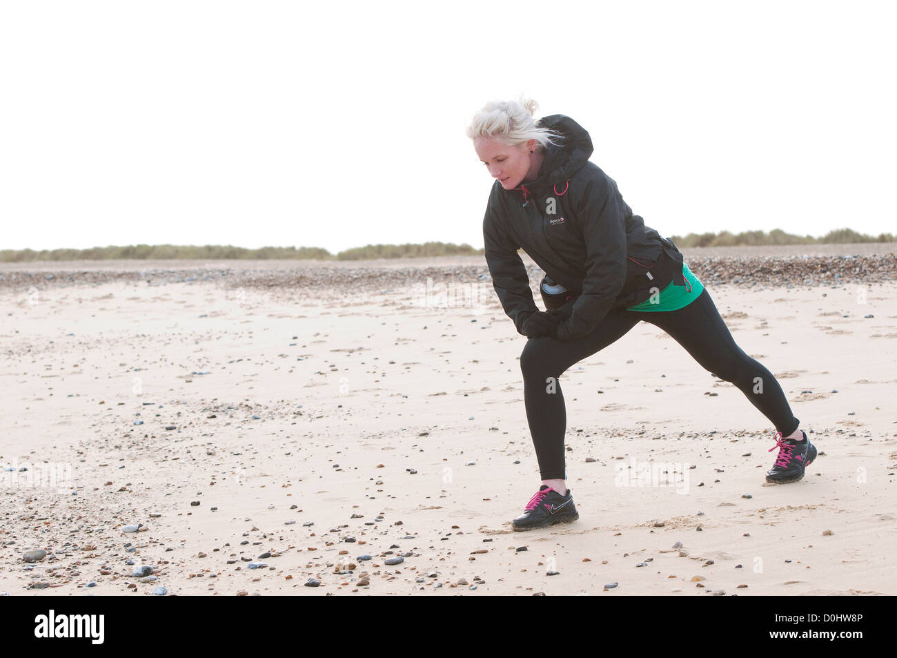 female jogger warming up on beach Stock Photo