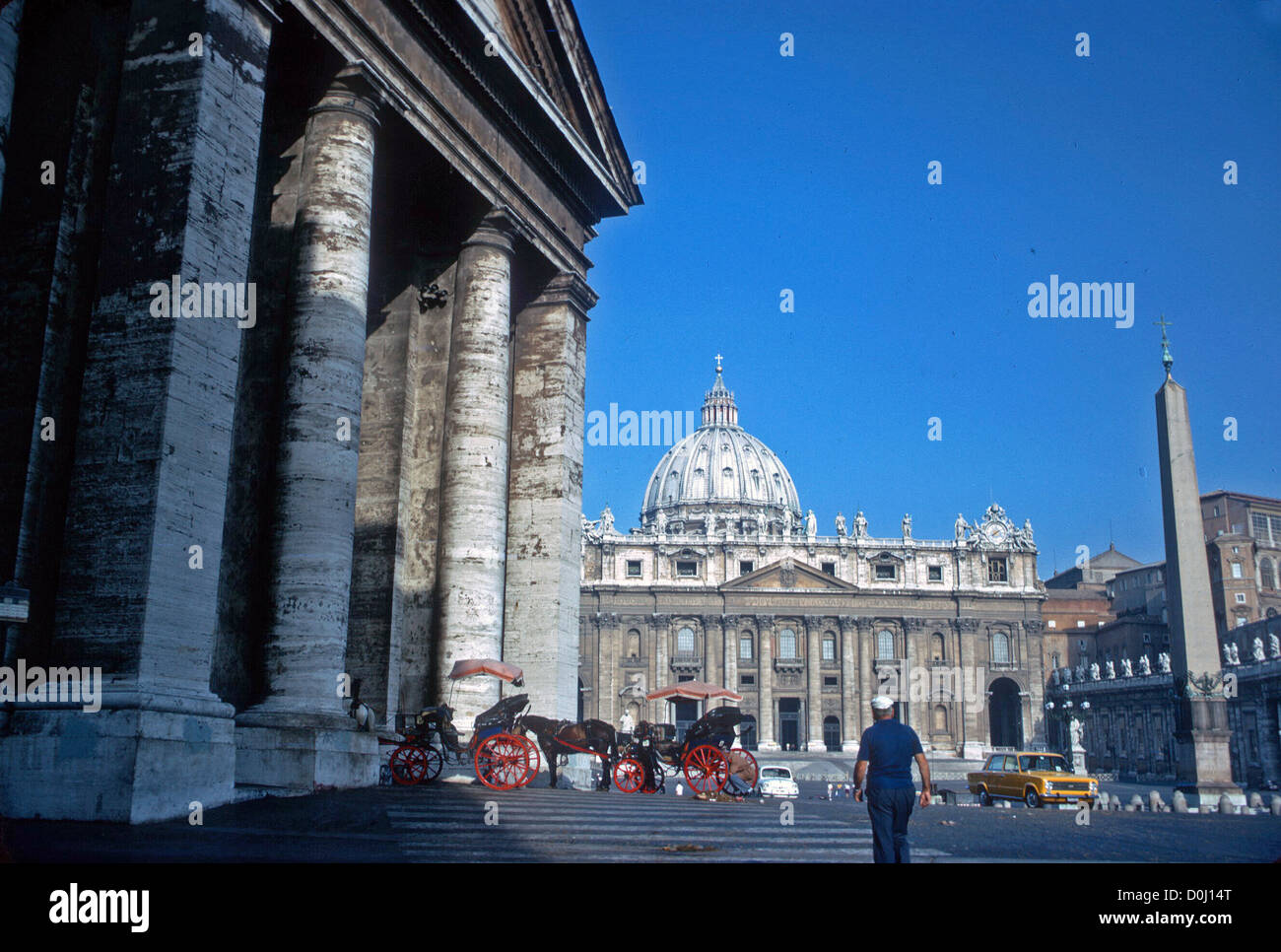 St Peter's Basilica with blue sky and carriages and figures lending scale. Rome Italy Stock Photo