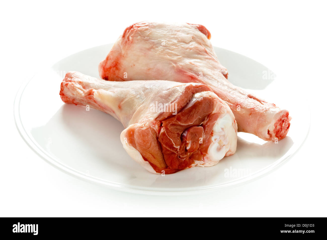 two raw lamb shanks on a plate isolated on white background Stock Photo