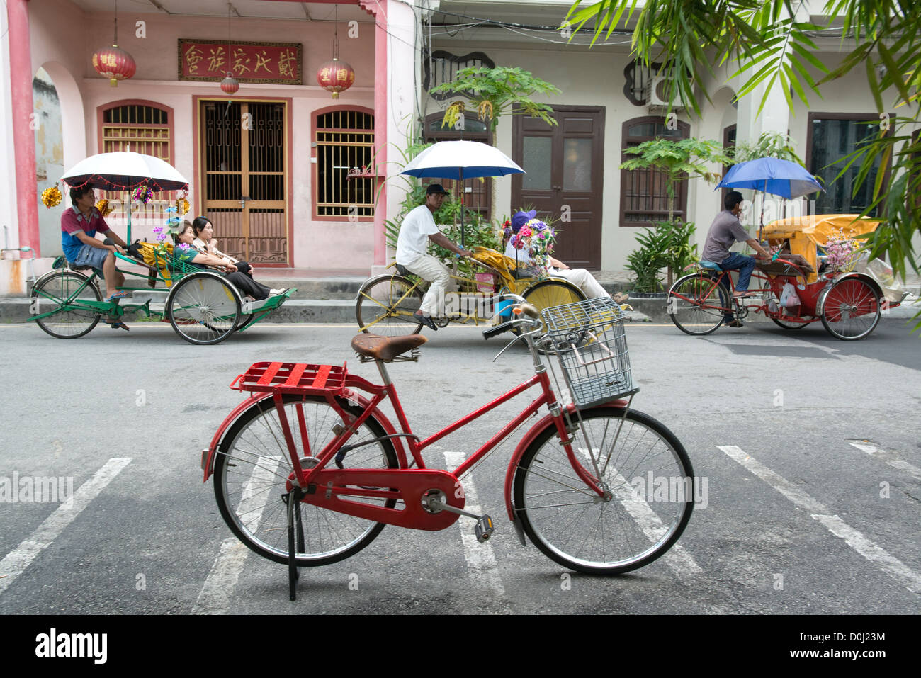 Tourists pass by in a fleet of Trishaws in Georgetown, Penang, Malaysia Stock Photo