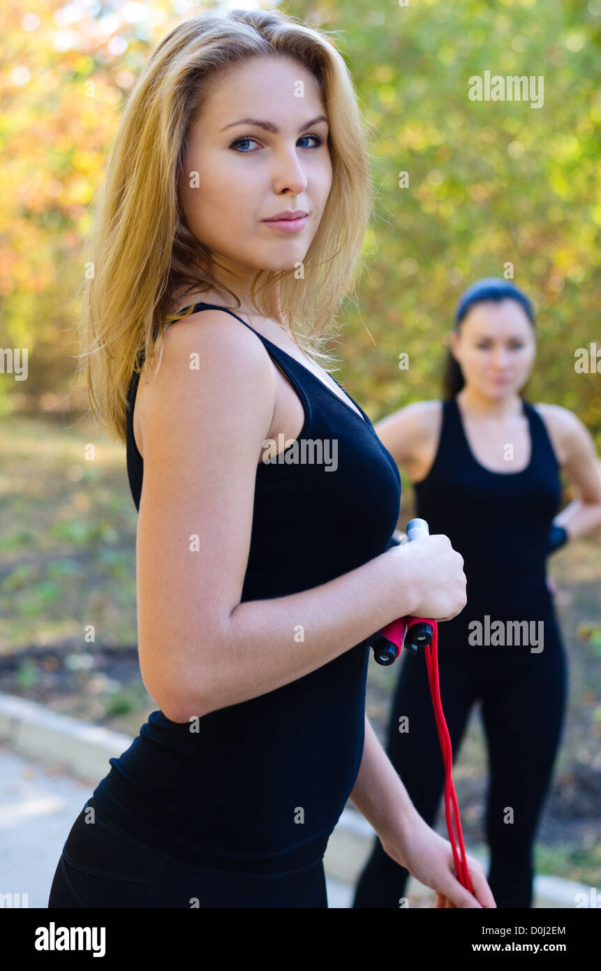 Two young beautiful women exercising with resistance bands in natural outdoor setting Stock Photo