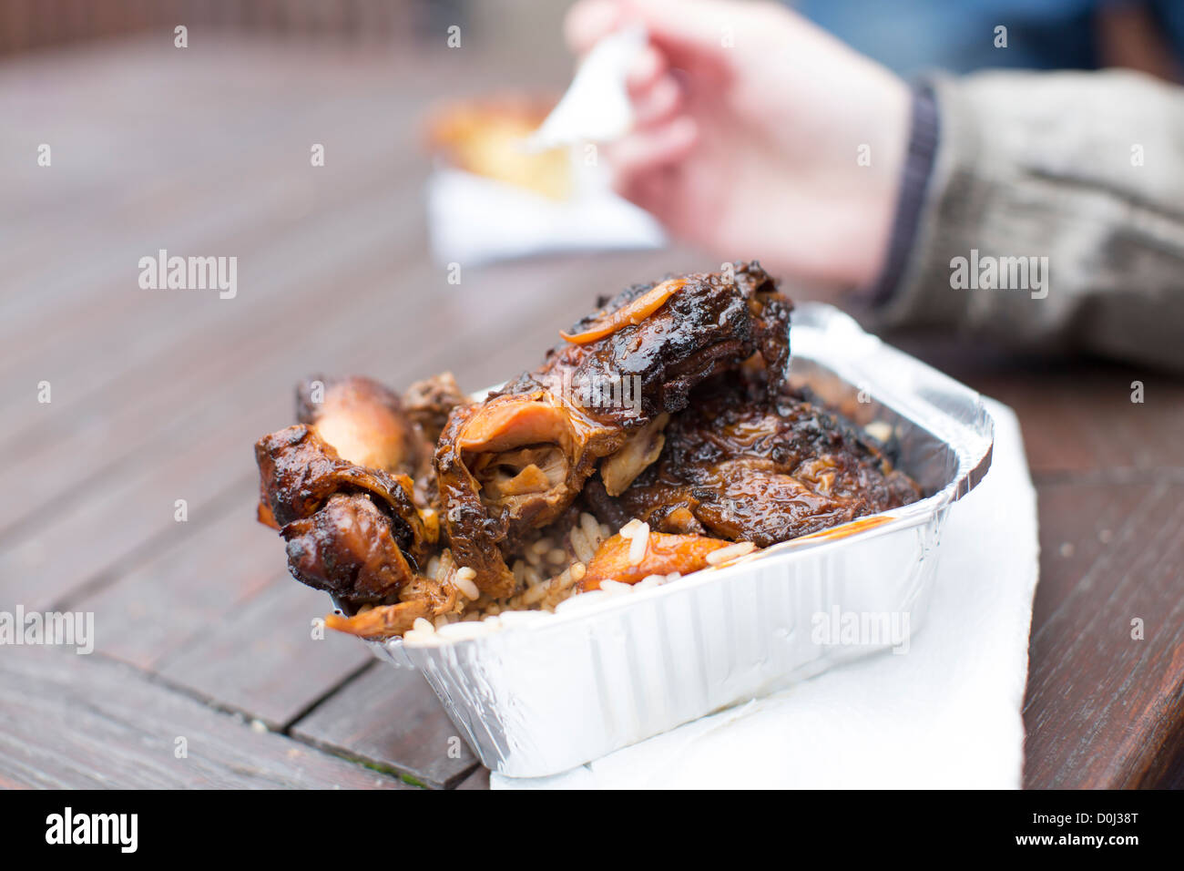 Woman eats a takeaway carton of pulled jerk chicken at the Love Food fayre in Paintworks, Bristol, England. Stock Photo