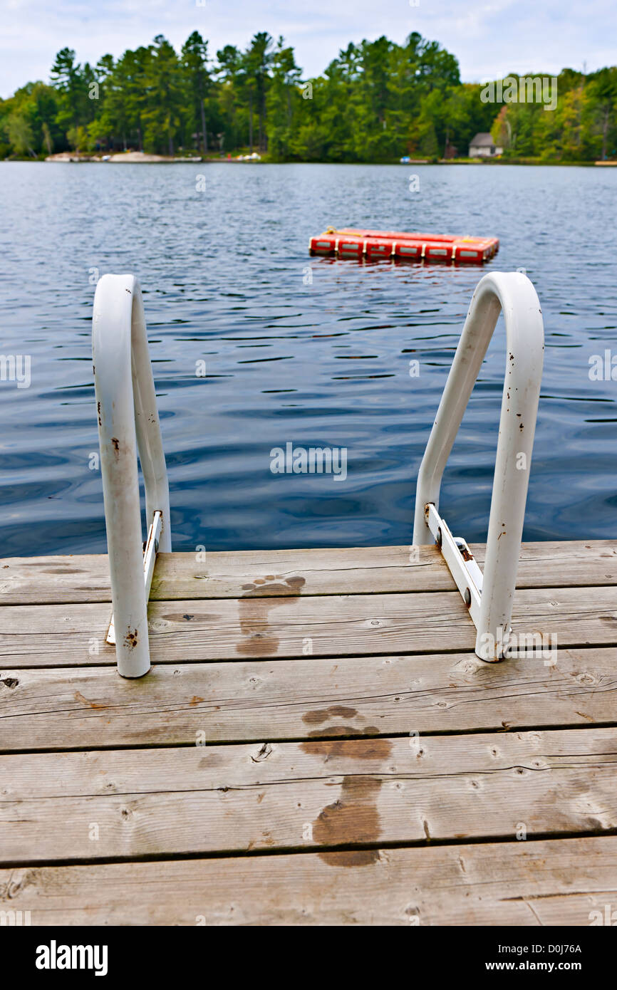 Wet footprints on dock with ladder and diving platform at lake in