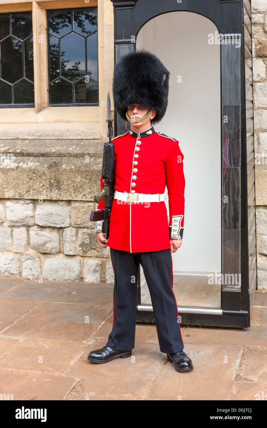A guard wearing a traditional bearskin stands guard outside the Jewel House in the Tower of London, London, England. Stock Photo