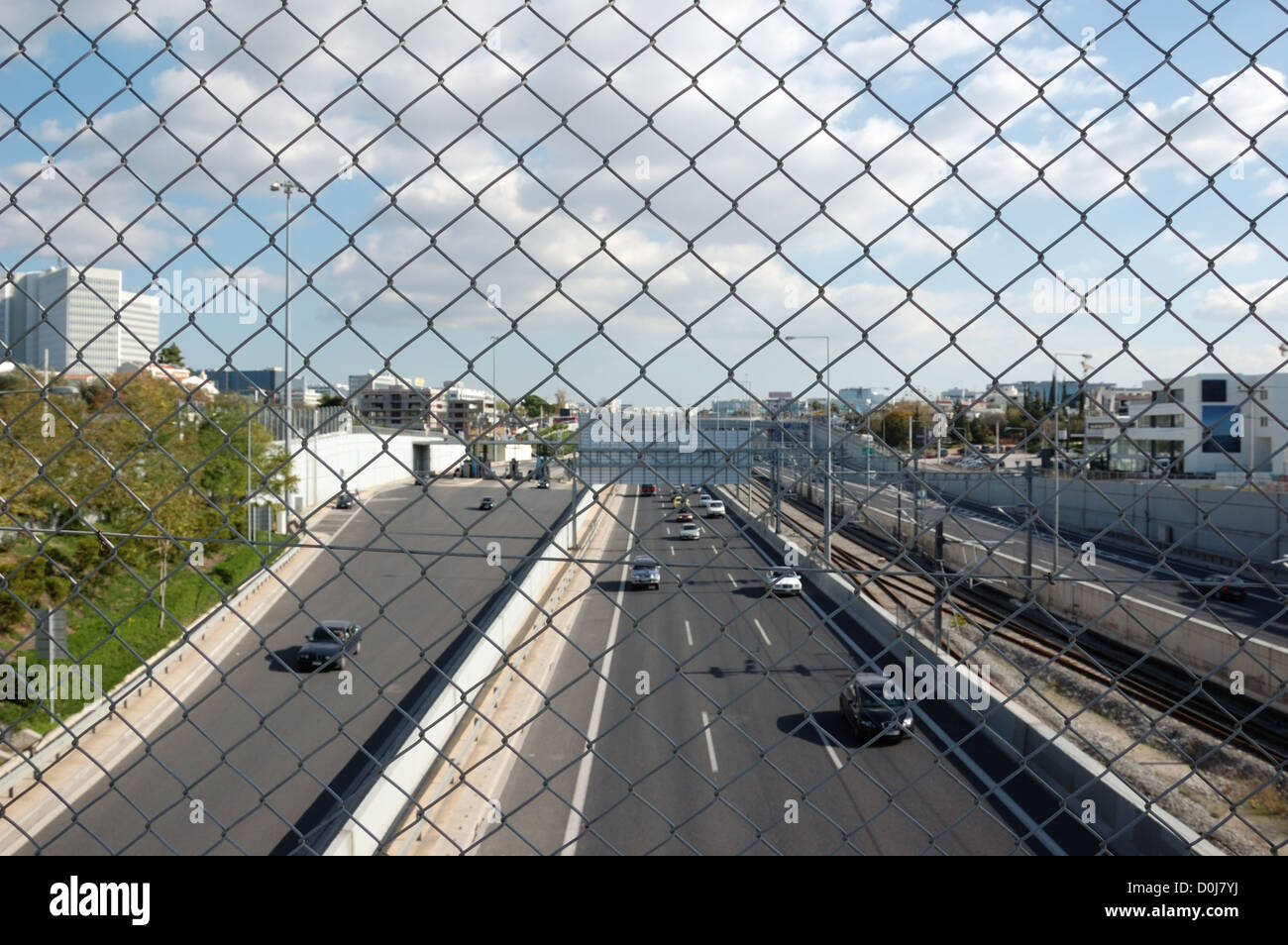 Cars on the motorway and chain link fence. City traffic. Stock Photo