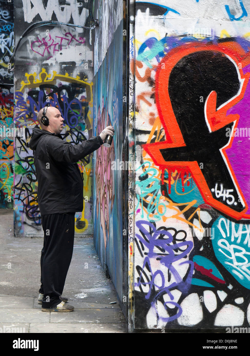 Man spraying at graffiti-land on the South Bank in London. Stock Photo