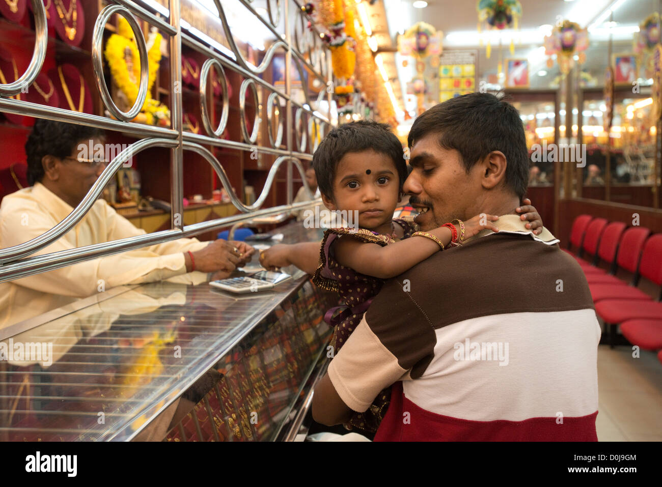 A father holds his daughter in a jeweller's shop in Georgetown's Little India, Penang, Malaysia Stock Photo