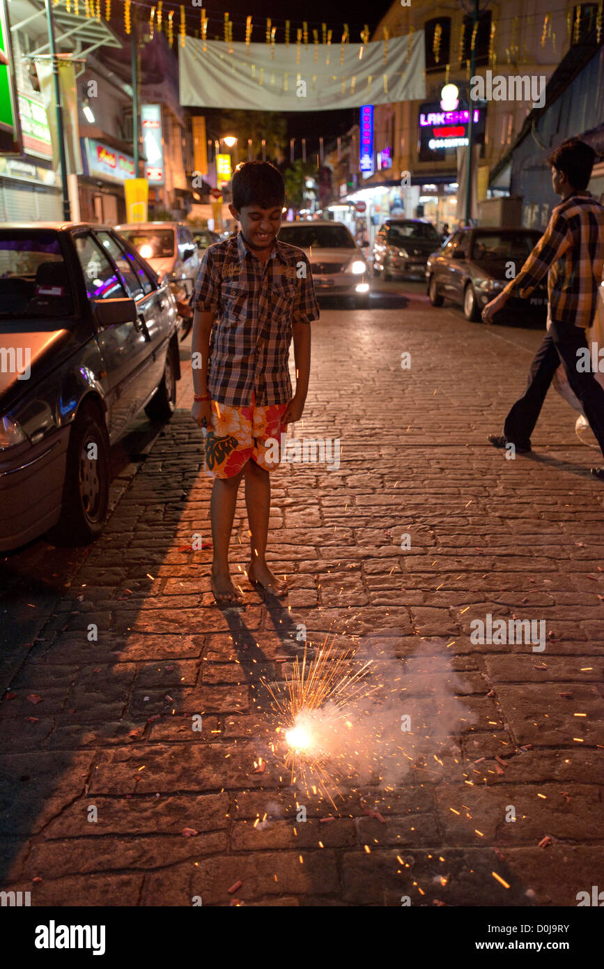 A young boy lets off a firecracker in the street in Georgetown's Little India, Penang, Malaysia Stock Photo