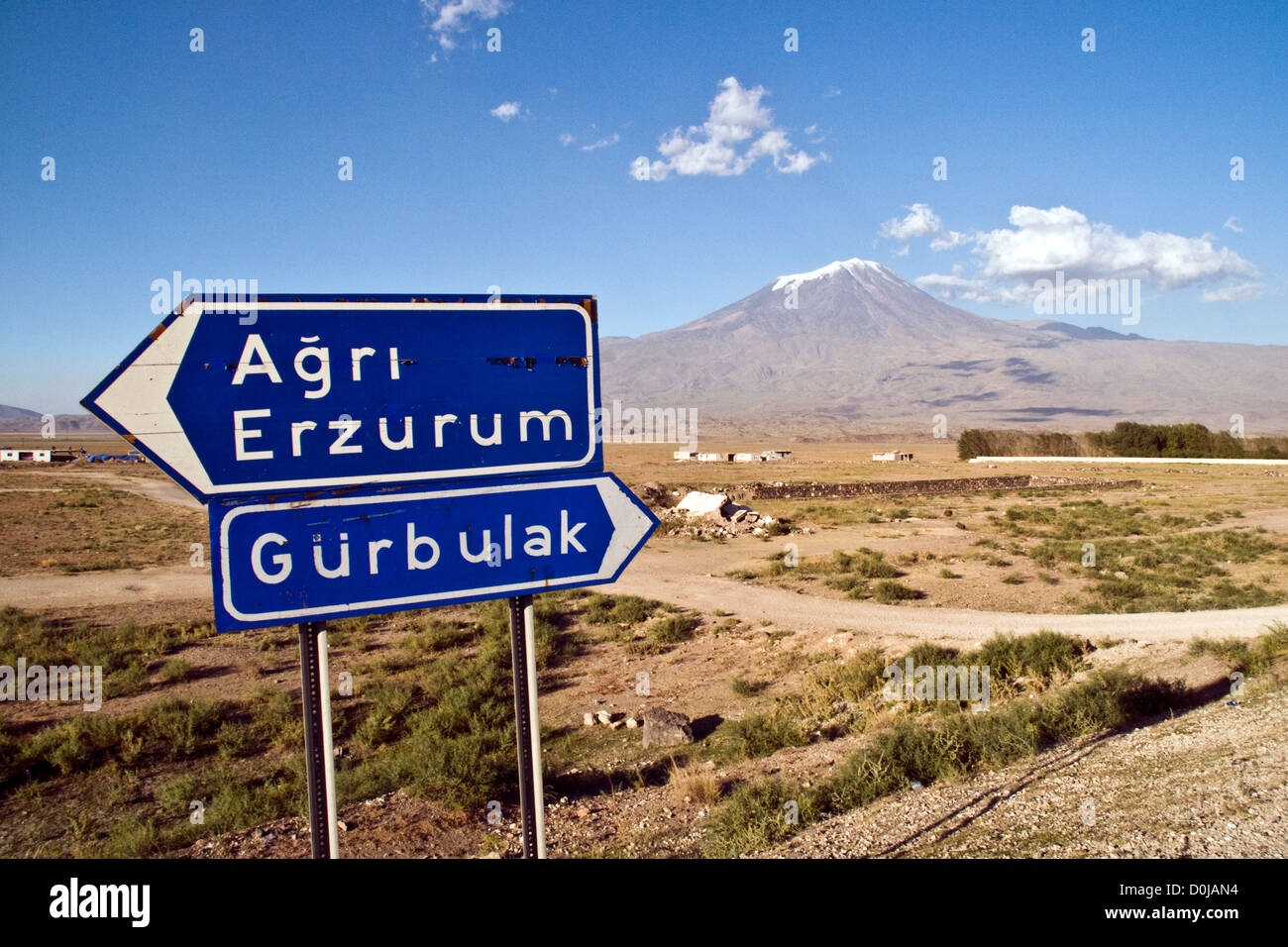 A Turkish road sign near Mount Ararat, or Agri Dagi, a snowcapped dormant volcanic massif towers over a tiny village in eastern Anatolia, Turkey. Stock Photo