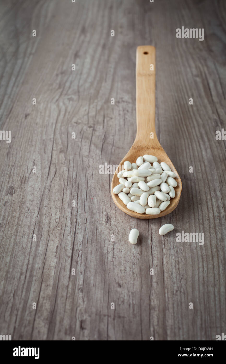 Bunch of fresh raw white beans on a wooden spoon Stock Photo