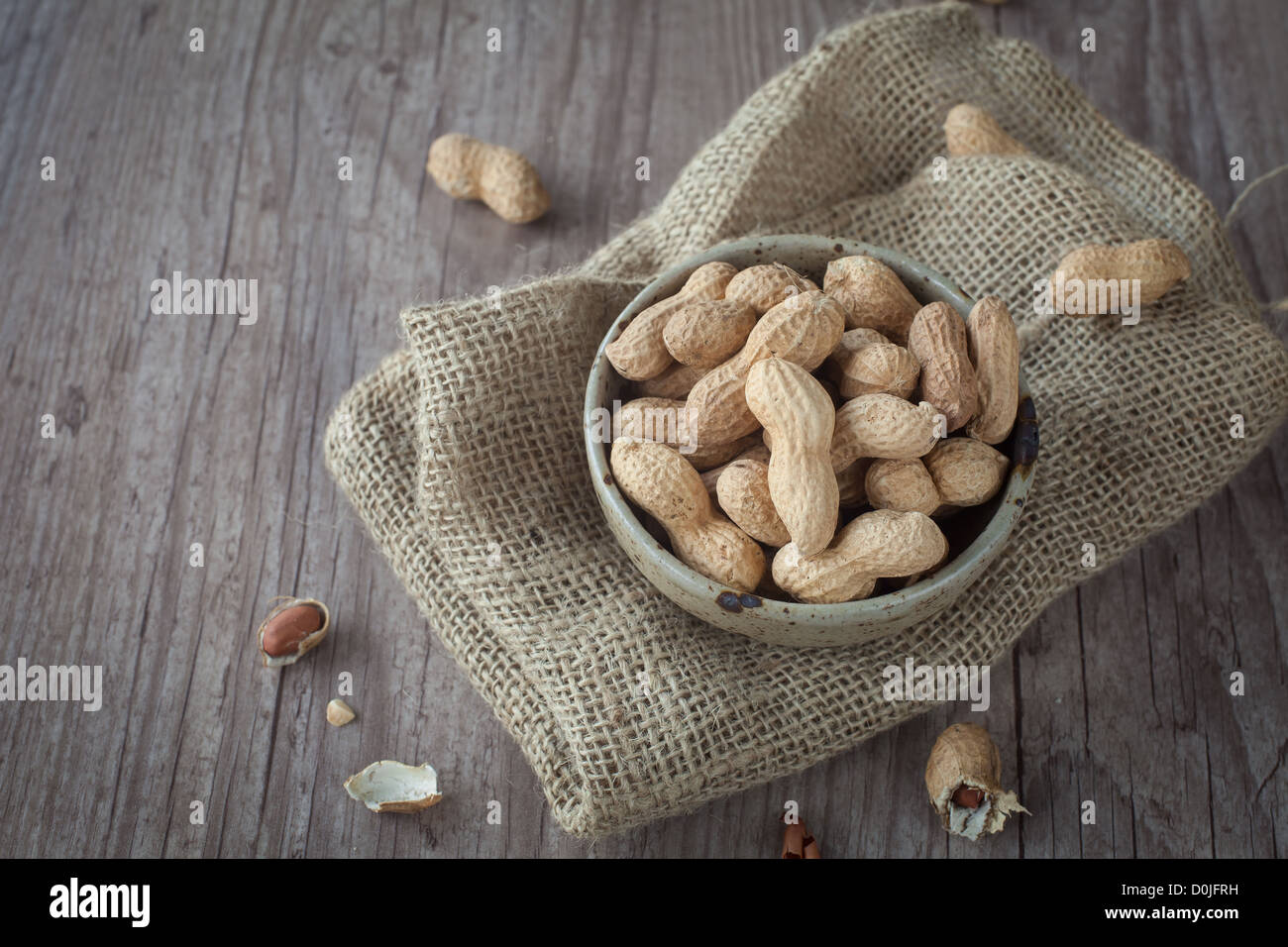 Bunch of peanuts in a bowl on wooden table Stock Photo