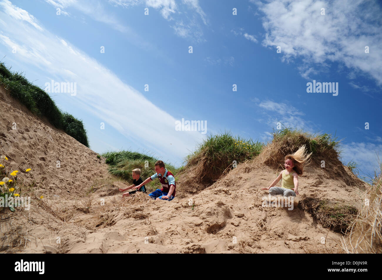 Children jumping off sand dunes into the soft sand below whilst walking