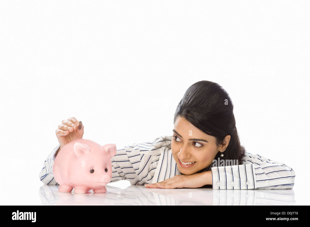 Businesswoman inserting a coin into a piggy bank Stock Photo Alamy