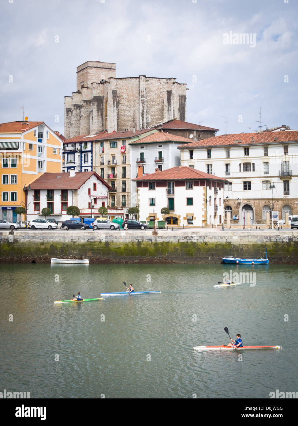 People kayaking near Zumaia, Guipuzkoa, in Northern Spain. The Basque-style Gothic church of San Pedro stands in the background Stock Photo