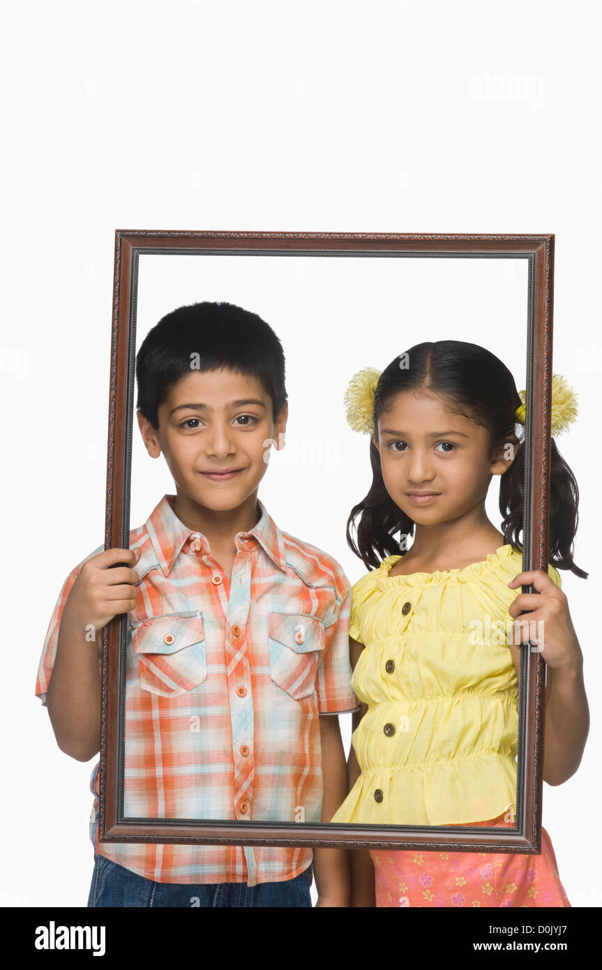 Portrait of a boy and a girl holding an empty picture frame Stock Photo ...