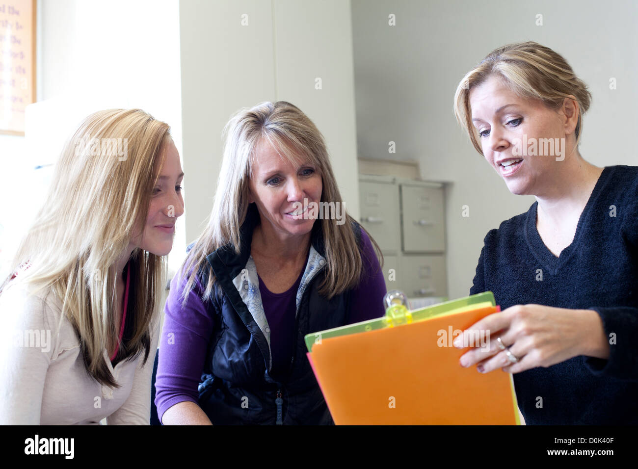 Teacher discussing school work with parent and student in classroom. Stock Photo