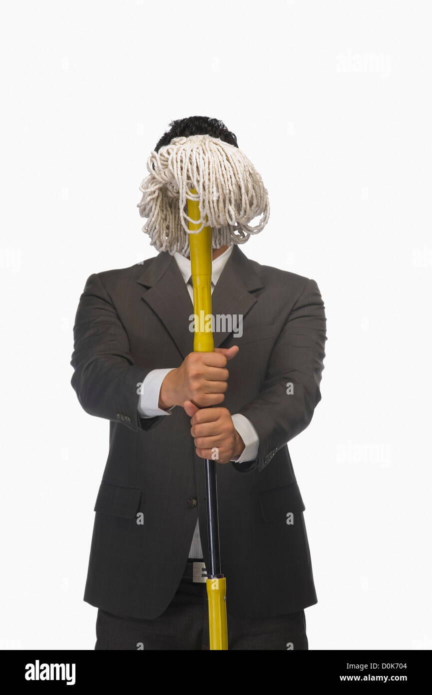 Businessman holding a broom in front of his face Stock Photo