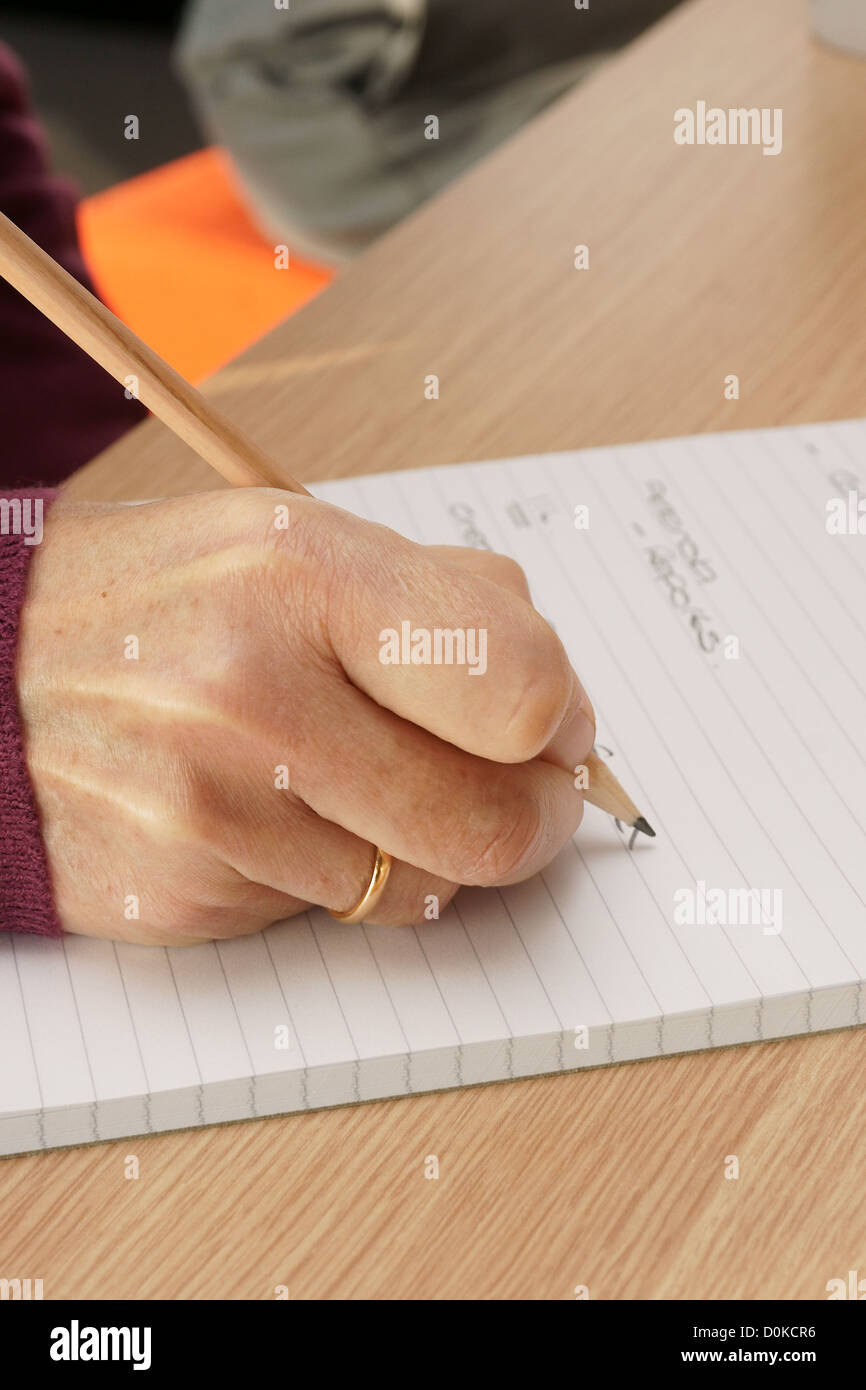 Female hand takes notes in business meeting with a pencil on lined