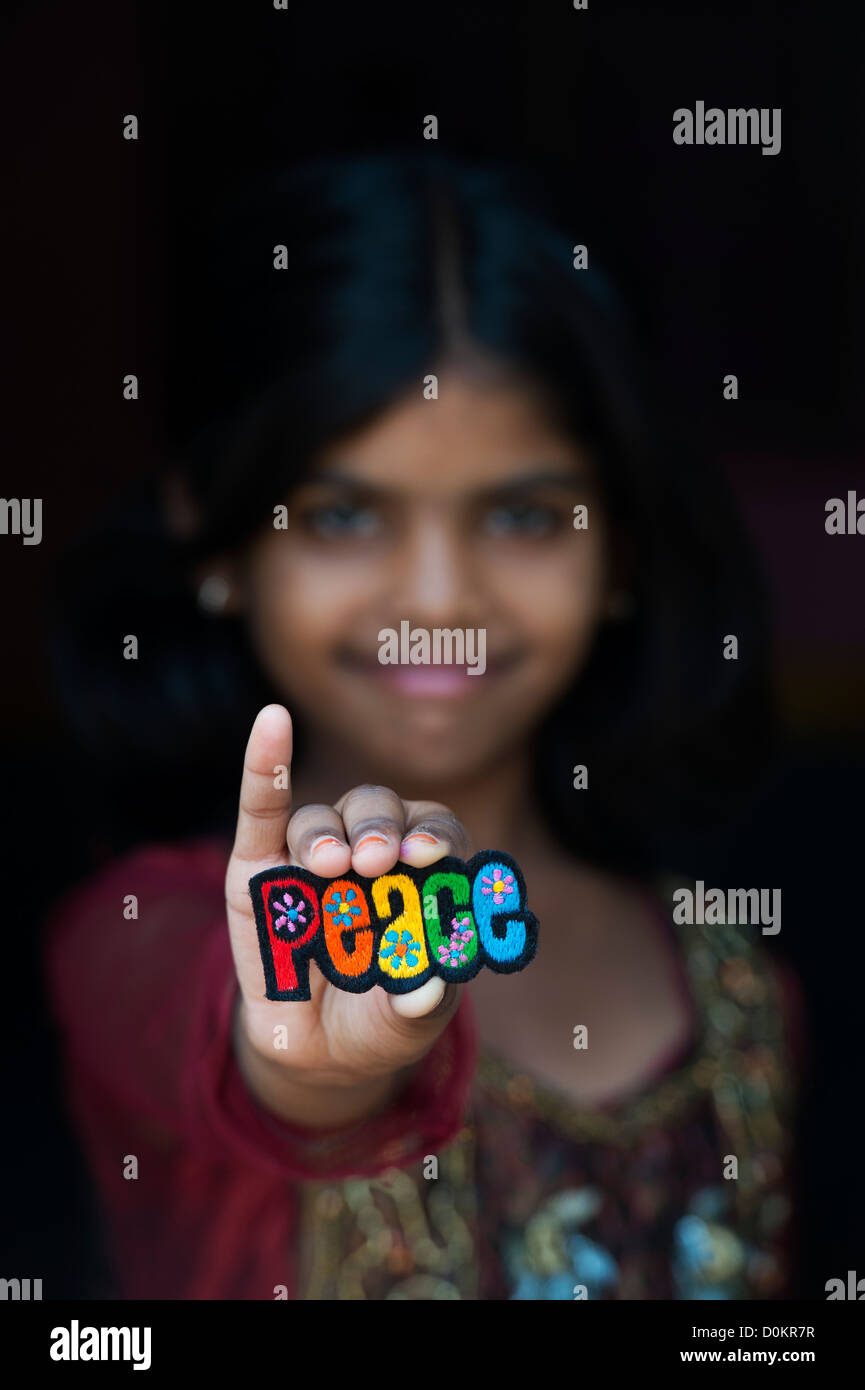 Smiling Indian girl holding a PEACE multicoloured embroidery patch Stock Photo